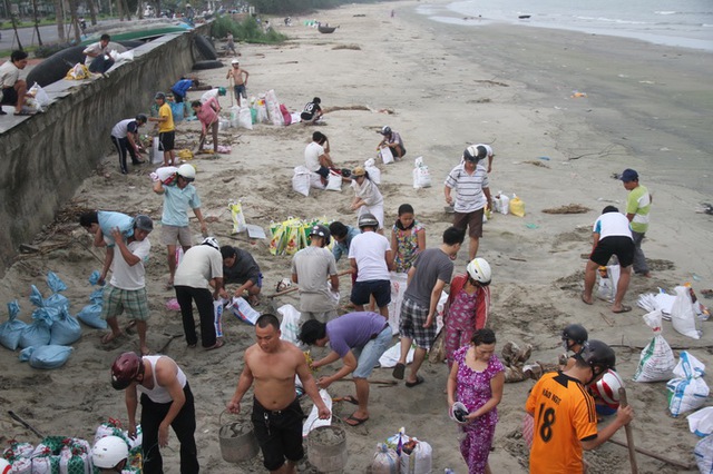 	Trên đường biển Nguyễn Tất Thành, Đà Nẵng, hàng trăm người dân vội vã xúc cát đóng bao chở về nhà. Ảnh: Tuổi trẻ