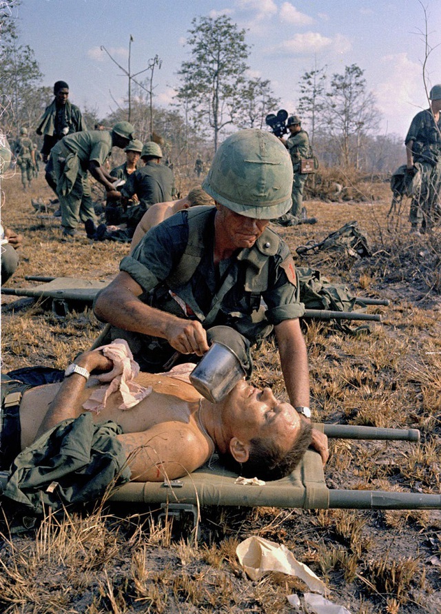 
	Lính Mỹ cho một đồng đội bị thương uống nước. Ảnh chụp ngày 2/4/1967.
