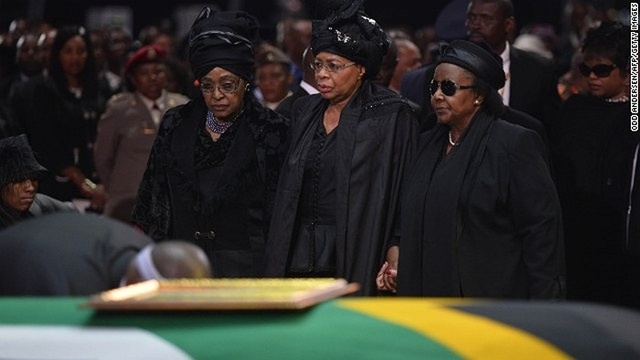  	Vợ cũ của ông Mandela, bà Winnie Madikizela Mandela (trái) và vợ hiện tại của ông là bà Graca Machel (giữa) đứng cạnh thi hài chồng