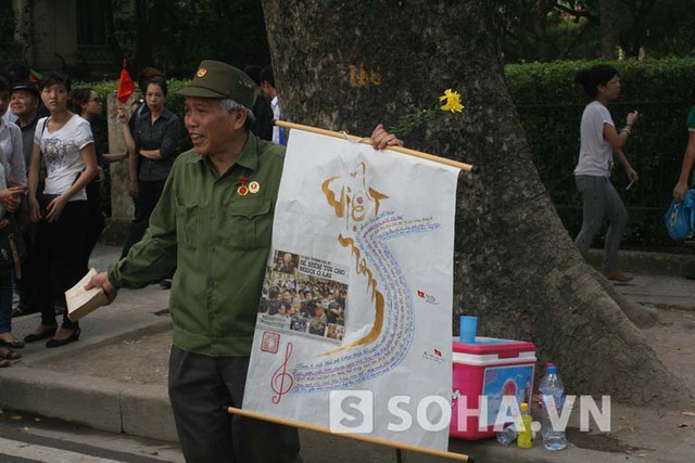 Ông Chính và bức vẽ bản đồ Việt Nam được bao phủ trên đó là lời bài hát Việt Nam quê hương tôi.