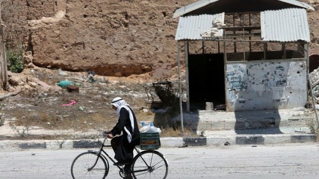  	Một người dân Syria đạp xe trong cảnh hoang tàn do các cuộc bạo động gây ra.