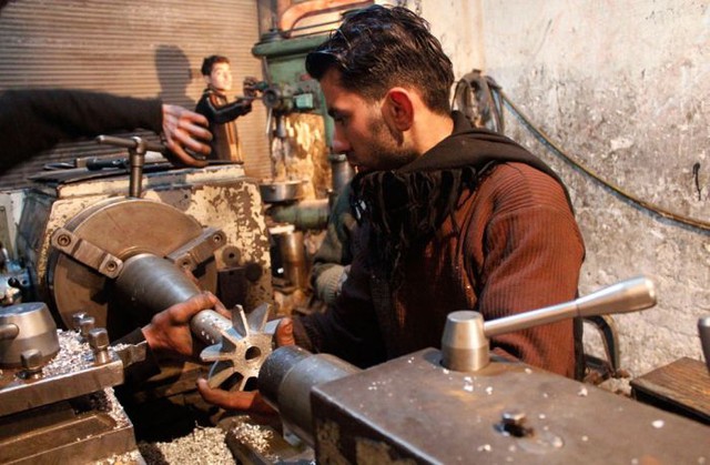 Người đàn ông làm việc với quả đạn cối tự tạo bên trong một nhà máy trước đây chuyển sản xuất sắt thép ở Aleppo (18/2/2013).