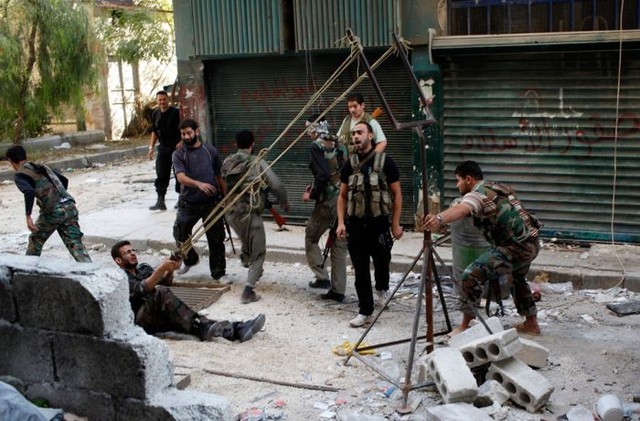 Các binh sĩ quân nổi dậy Syria sử dụng súng cao su để khởi động một quả bom tự tạo trong cuộc đụng độ với binh sĩ ủng hộ chính phủ tại thành phố Aleppo (Ngày 15/10/2012).