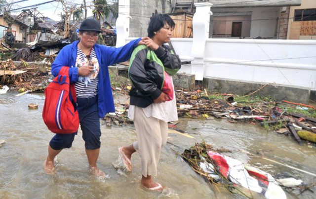 Hai người phụ nữ dắt díu nhau trên con đường ngập nước mưa từ Tacloban đi Basey, nơi họ hy vọng gặp được người quen ở đó để nương tựa.