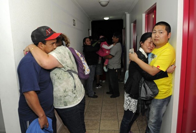 Mọi người ôm nhau lo lắng trên hành lang của một tòa nhà chung cư trong khi tránh sóng thần có thể xảy ra sau trận đông đất mạnh 8,2 độ richter ở Iquique, Chile.