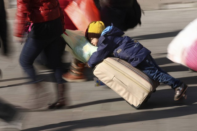 Một cậu bé ôm va li đang được kéo trước nhà ga tàu hỏa ở Thanh Đảo, Trung Quốc. Hàng triệu người dân Trung Quốc đổ về quê trong dịp nghỉ Tết Nguyên Đán.