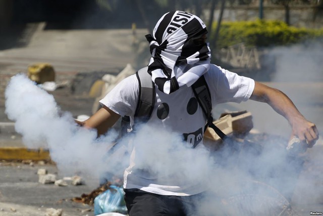 Một người biểu tình ném lựa đạn hơi cay trả lại cảnh sát ở Caracas, Venezuela.