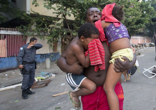Một người đàn ông vừa chạy vừa bế hai đứa trẻ trong cuộc trục xuất những người dân ở trái phép tại các tòa nhà bỏ hoang của một công ty viễn thông ở Rio de Janeiro, Brazil.