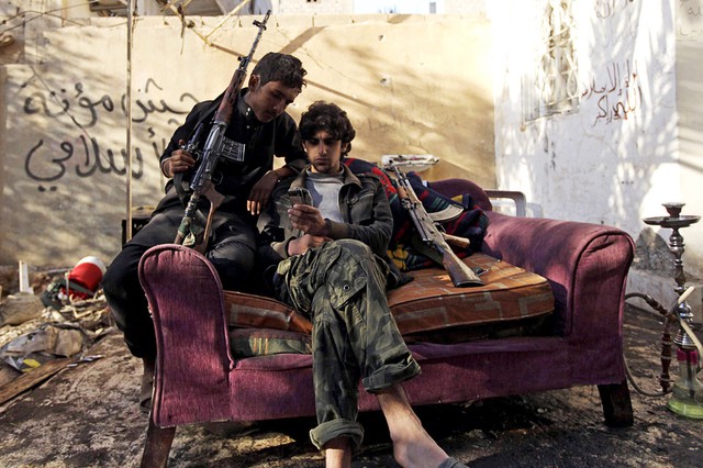 Các chiến binh phiến quân ngồi xem điện thoại di động tại thành phố Deir al-Zor, Syria.