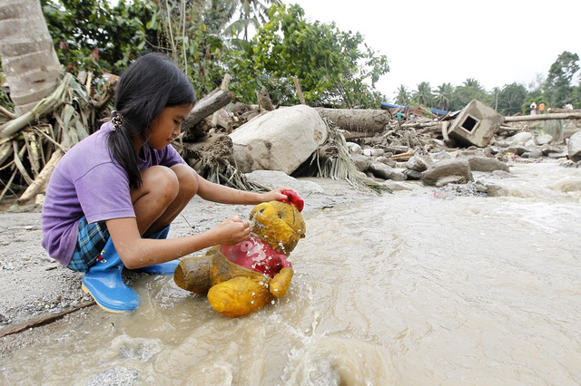Một bé gái rửa sạch gấu bông sau khi nước lũ rút khỏi ngôi làng Marayag trên đảo Mindanao, Philippines.