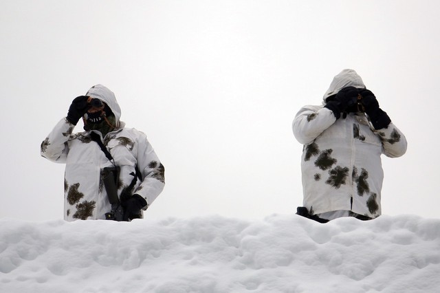 Các thành viên của quân đội Thụy Sĩ dùng ống nhòm để quan sát từ trên mái nhà ở Davos.
