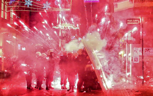 Cảnh sát chống bạo động đứng trú sau khiên khi pháo bắn bởi người biểu tình phát nổ trên đường phố ở Istanbul, Thổ Nhĩ Kỳ.
