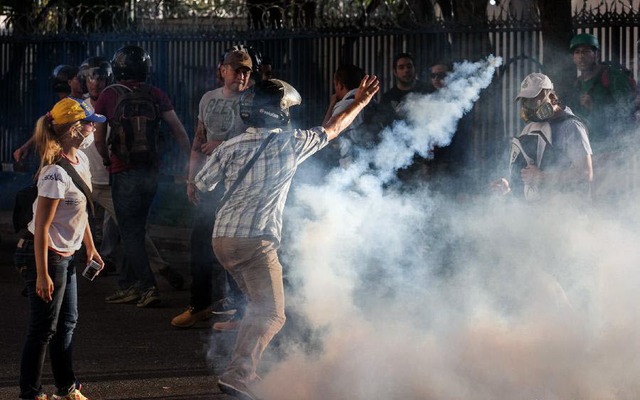 Sinh viên biểu tình ném lựu đạn hơi cay trả lại cảnh sát trong cuộc đụng độ ở Caracas, Venezuela.