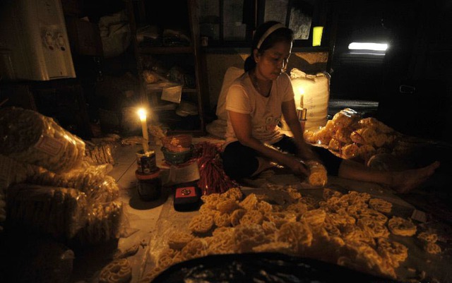 Một phụ nữ phải thắp nến gói bánh vì mất điện tại Jakarta, Indonesia.