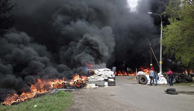 Khói đen bốc lên từ những chiếc lốp xe đang cháy tại một điểm chốt sau cuộc tấn cống của quân đội chính phủ ở ngoại ô thành phố Slovyansk, Ukraine.