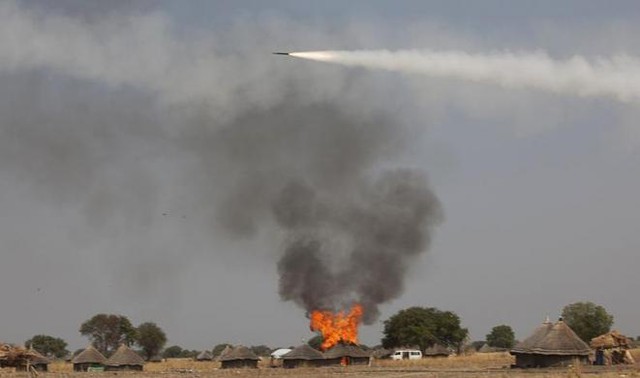 Rocket phóng bởi quân đội chính phủ bay trên một ngôi nhà đang cháy do bị trúng một quả rocket khác tại Mathiang, Nam Sudan.