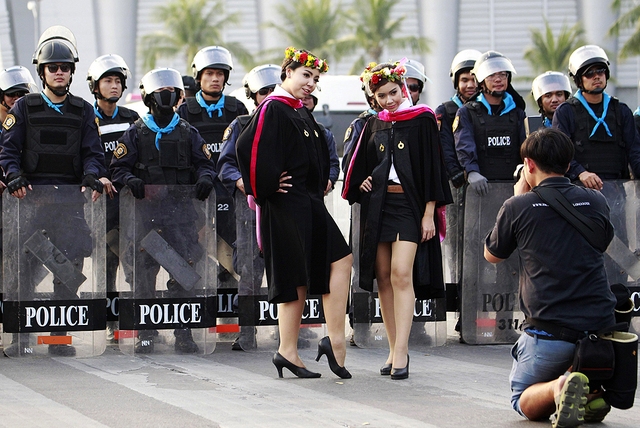 Các nữ sinh viên mới tốt nghiệp từ trường đại học Rangsit chụp ảnh cạnh một nhóm cảnh sát chống bạo động ở Bangkok, Thái Lan.