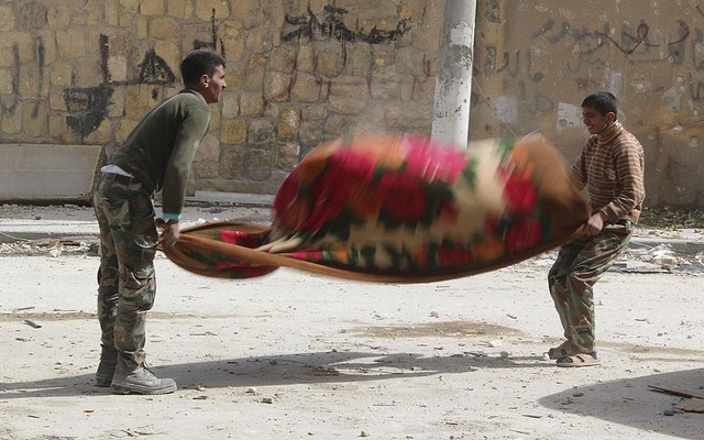 Các chiến binh phiến quân Syria vệ sinh chăn tại hiện trường bị không kích bởi quân đội chính phủ ở Aleppo.