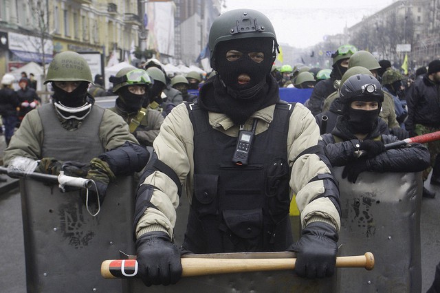 Người biểu tình chống chính phủ được trang bị dùi cui và khiên để ngăn chặn những người ủng hộ chính phủ dỡ bỏ hàng rào trên phố ở Kiev, Ukraine.
