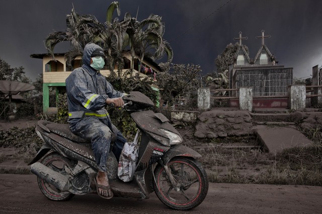 Tro bụi phun trào từ núi lửa Sinabung phủ đầy một người đi xe máy ở Karo, Indonesia.