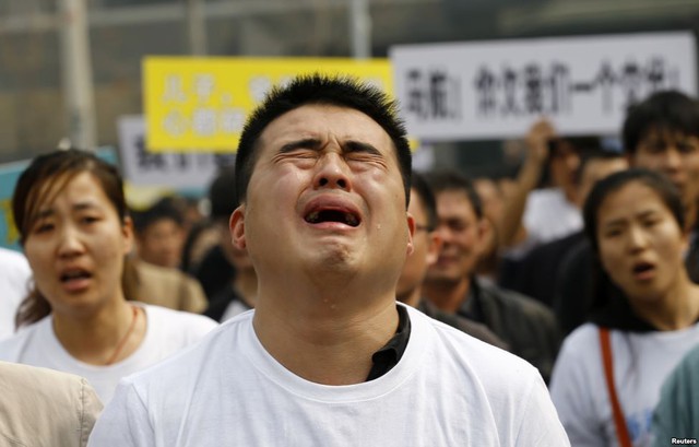 Một thân nhân của hành khách trên chuyến bay MH370 của Malaysia Airlines khóc khi hô khẩu hiệu trong cuộc biểu tình trước đại sứ quán Malaysia ở Bắc Kinh, Trung Quốc.