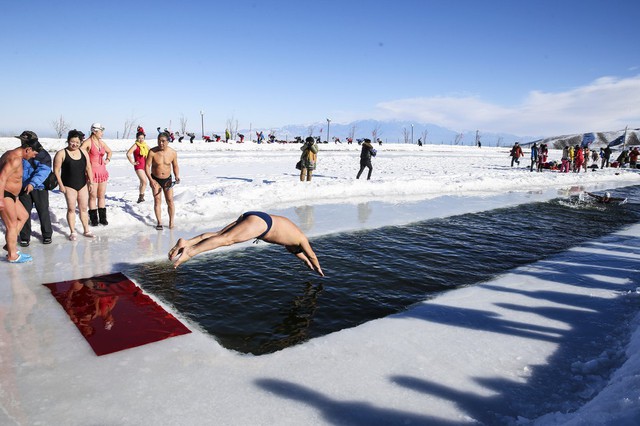 Một người đàn ông nhảy xuống nước băng trong ngày khai mạc lễ hội băng tuyết ở khu tự trị Tân Cương, Trung Quốc.