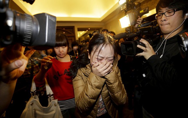 Một người thân của hành khách trên chuyến bay MH370 của hãng hàng không Malaysia Airlines khóc khi đi qua các nhà báo tại sân bay ở Bắc Kinh, Trung Quốc.