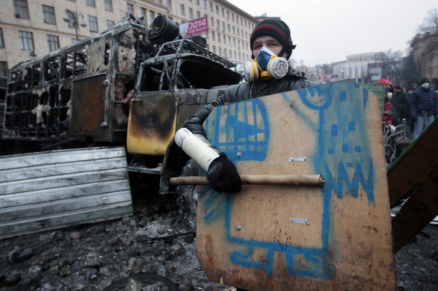 Người biểu tình đứng trước hàng rào chặn đường trong cuộc đụng độ với cảnh sát ở Kiev, Ukraine.