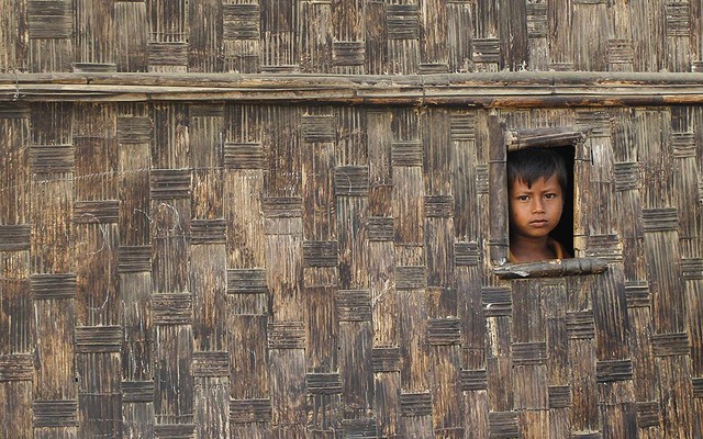Một cậu bé nhìn ra ngoài từ ngôi nhà tạm tại trại tị nạn Rohingya ở Sittwe, Myanmar.