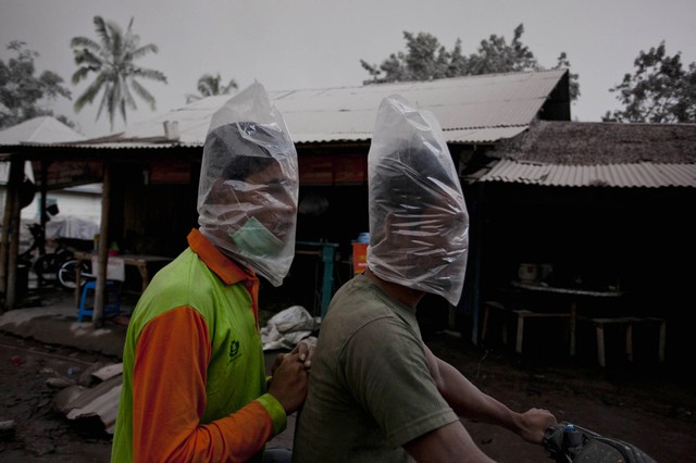Hai người đi xe máy đội túi bóng để bảo vệ mặt khỏi tro bụi phun trào từ núi lửa Sinabung ở North Sumatra, Indonesia.