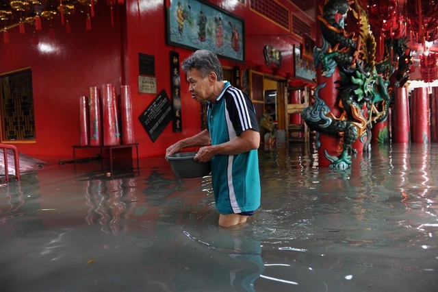 Một người đàn ông lội qua nước lũ bên ngoài một ngôi chùa ở Jakarta, Indonesia.