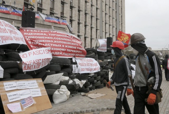 Những người biểu tình ủng hộ Nga đi qua rào chắn được họ dự lên trước tòa nhà thị chính ở Donetsk, Ukraine.