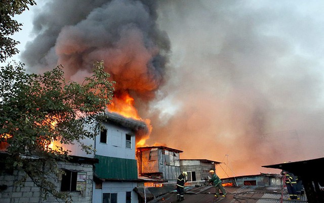 Lính cứu hỏa cố gắng dập tắt đám cháy bùng phát tại một khu ổ chuột ở thành phố Quezon Manila, Philippines.