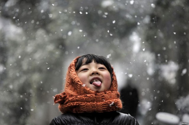 Một bé gái thè lưỡi nếm tuyết trên đường phố ở Hợp Phì, tỉnh An Huy, Trung Quốc.