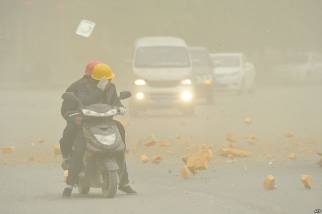 Mọi người che mặt khi gió mạnh thổi vật liệu xây dựng từ một tòa nhà xuống đường ở Hami, Khu tự trị dân tộc Duy-ngô-nhĩ, Trung Quốc.