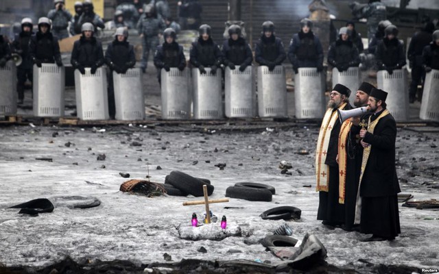 Một linh mục phát biểu qua loa trước cảnh sát chống bạo động và người biểu tình chống chính phủ trên đường phố ở Kiev, Ukraine.