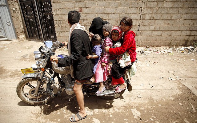 Một người đàn ông đi xe máy chở trẻ em tới một trung tâm tiêm văc-xin ở Sanaa, Yemen.