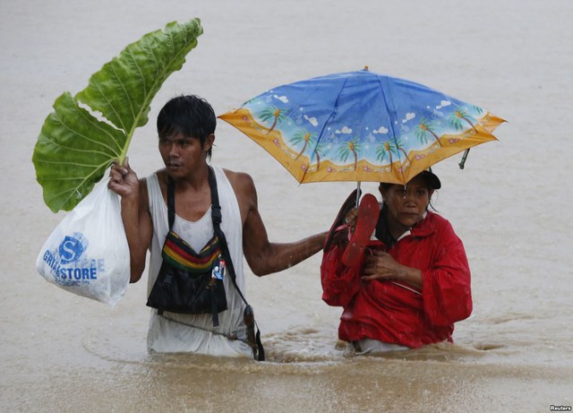 Một cặp vợ chồng lội trên đường ngập lụt dưới trời mưa ở Kabadbaran, Agusan del Norte, Philippines.