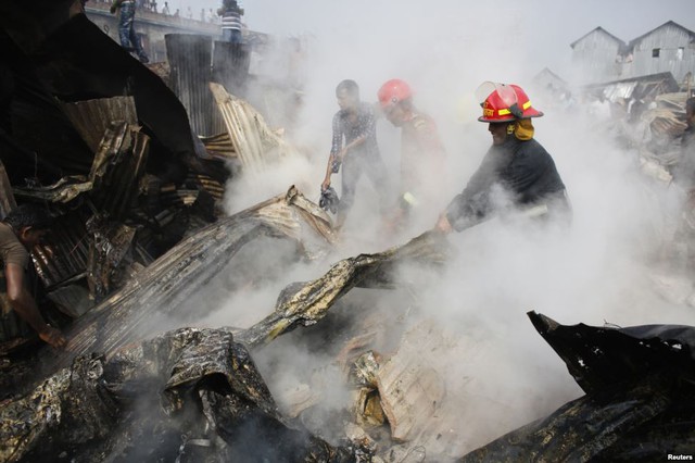 Lính cứu hỏa cố gắng dập tắt đám cháy tại một khu ổ chuột ở Dhaka, Bangladesh.