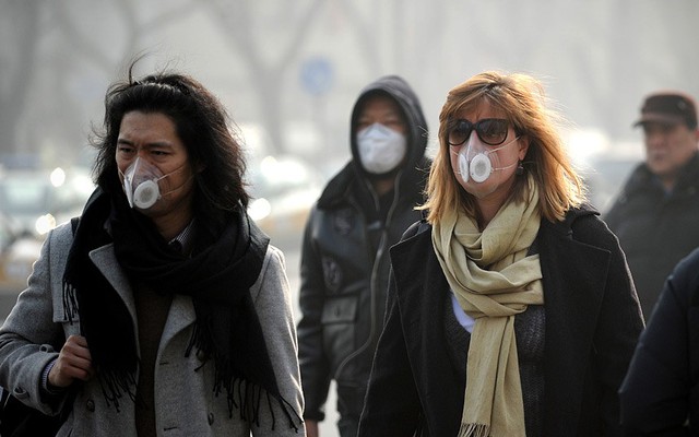 Mọi người đeo mặt nạ trong khi đi bộ dọc một đường phố ở Bắc Kinh, Trung Quốc. Không khí ô nhiễm ở thủ đô của Trung Quốc đã vượt 20 lần so với mức cho phép.