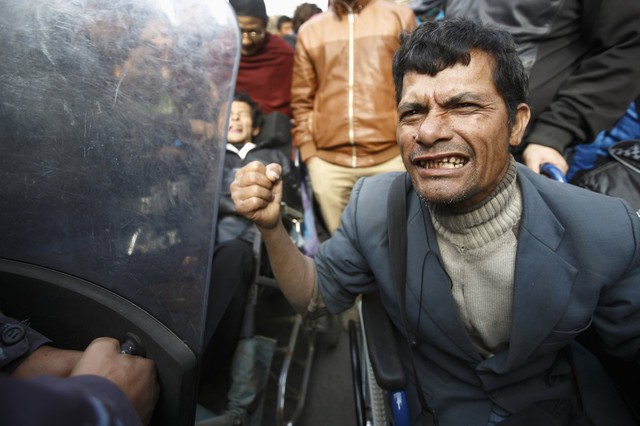 Một người đàn ông khuyết tật cố gắng tấn công cảnh sát trong cuộc biểu tình ở Katmandu, Nepal.
