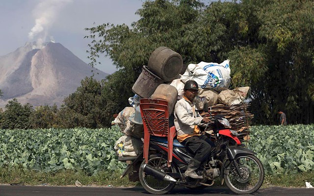 Người dân sơ tán đồ tạc trên một chiếc xe máy khi núi lửa Sinabung tiếp tục phun trào tro bụi gần ngôi làng Simpang Empat ở Karo, Indonesia.