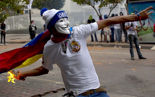 Một người biểu tình đeo mặt nạ ném bom xăng vào cảnh sát trong cuộc đụng độ ở Caracas, Venezuela.