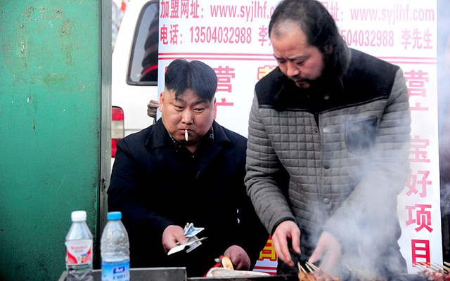 Một người đàn ông bán thịt nướng trên phố, có ngoại hình giống nhà lãnh đạo Triều Tiên Kim Jong-un, đang đếm tiền tại quầy hàng ở Thẩm Dương, tỉnh Liêu Ninh, Trung Quốc.