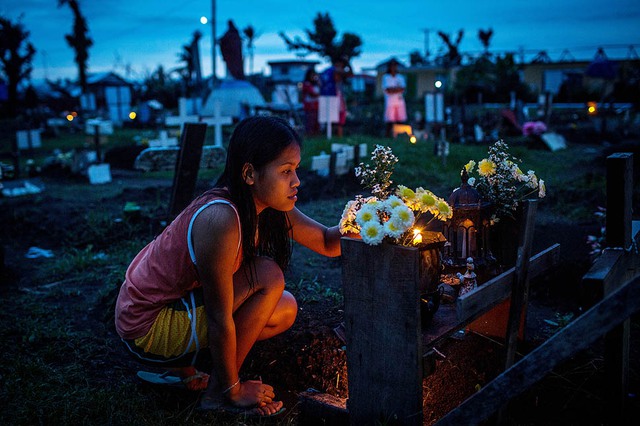 Một phụ nữ chăm nom mộ của người thân tại bãi chôn tập thể tại San Joaquin Parish ở Tacloban, Philippines. Mọi người tiếp tục tái thiết cuộc sống 5 tháng sau khi xảy ra siêu bão Haiyen.