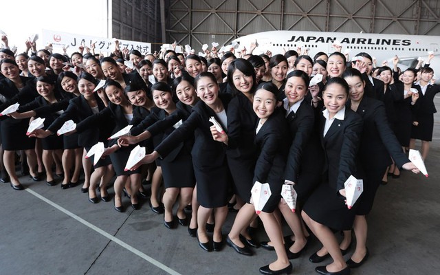 Các nhân viên mới của hãng hàng không Japan Airlines cầm máy bay giấy trong khi chụp ảnh sau lễ chào mừng gần sân bay Haneda ở Tokyo.