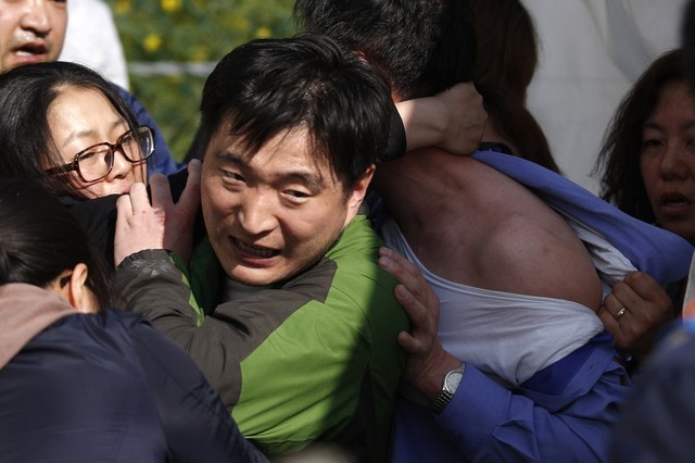 Thân nhân của hành khách mất tích trên phà Sewol kéo áo Choi Sang-hwan, Phó tư lệnh Lực lượng bảo vệ bờ biển Hàn Quốc và một quan chức chính phủ bên ngoài văn phòng của họ trên đảo Jindo.