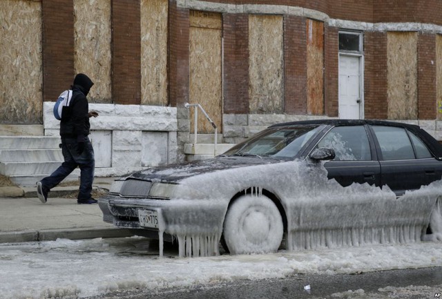 Người đàn ông đi qua chiếc ô tô bị đóng băng một phần ở Baltimore, Maryland, Mỹ.