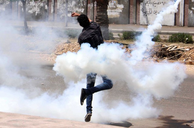Một người biểu tình ném lựu đạn hơi cay trả lại cảnh sát chống bạo động bên ngoài trường đại học al-Azhar ở Cairo, Ai Cập.