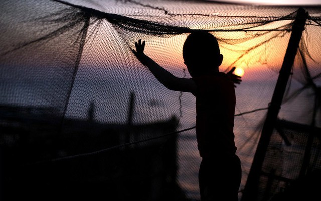 Một cậu bé người Palestine chơi với lưới đánh cá khi mặt trời lặn tại thành phố Gaza.